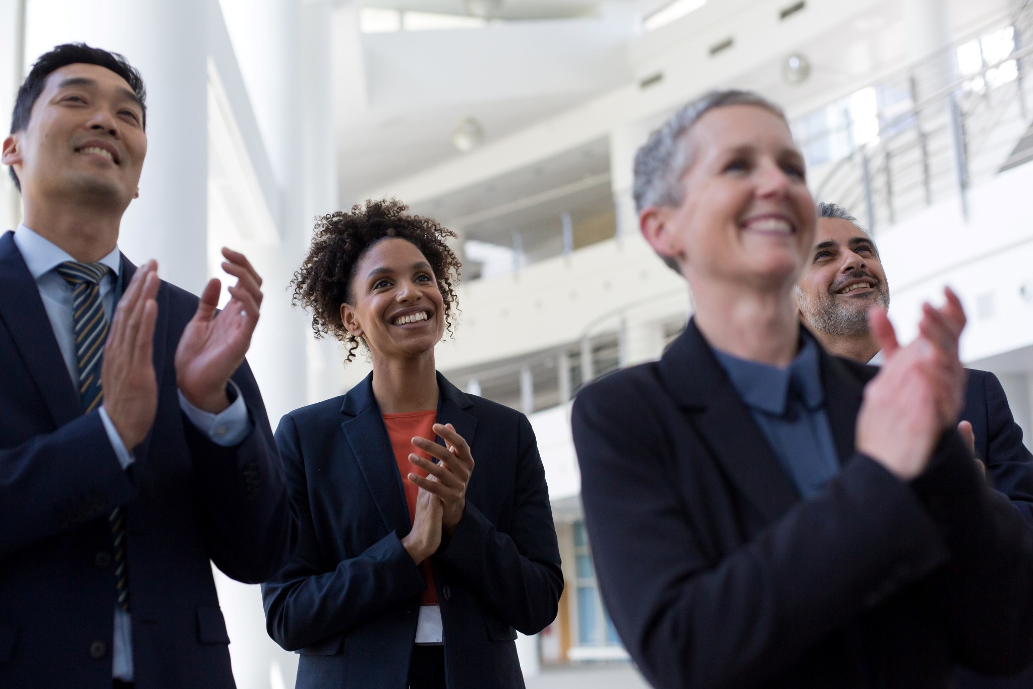 Professionals in a modern business setting applauding during an event